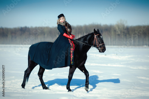 A girl in a long black dress with a dark horse © liyasov