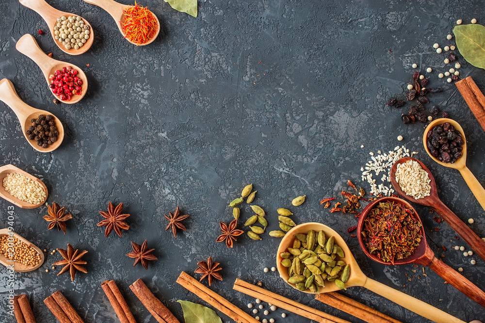 spices and herbs over black stone background.