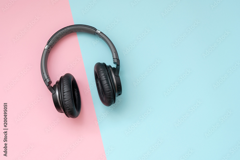 Modern black wireless headphones on a pink and blue background. The concept of music and fashion. Minimalism. - obrazy, fototapety, plakaty 