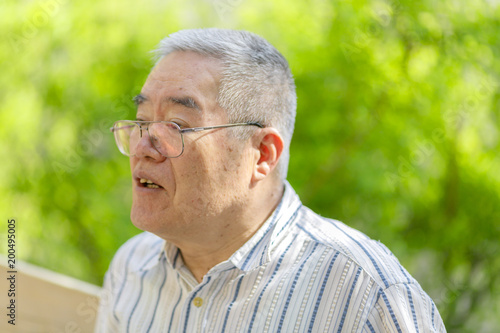 自然の緑背景とシニア日本人男性