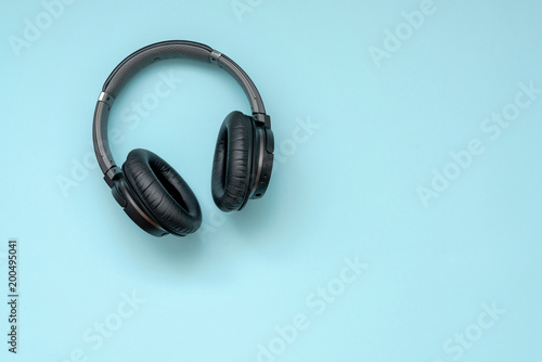 Modern black wireless headphones on a blue background. The concept of music and fashion.