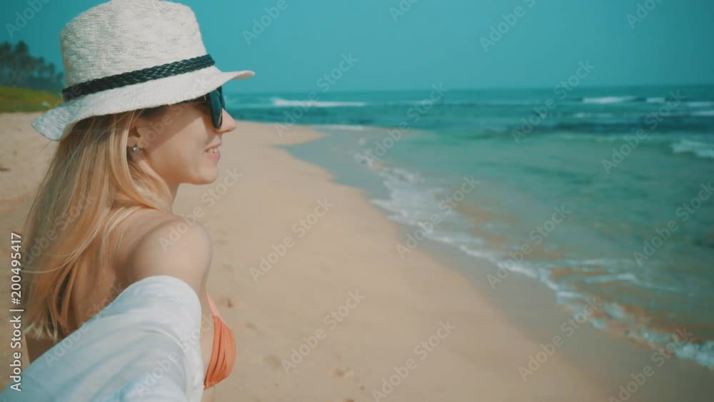 Woman relaxing and walking on the ocean beach under blue sky in sunny day. Seascape view with palms. Woman relaxing and walking on the ocean beach under blue sky in sunny day. Seascape view with palms.