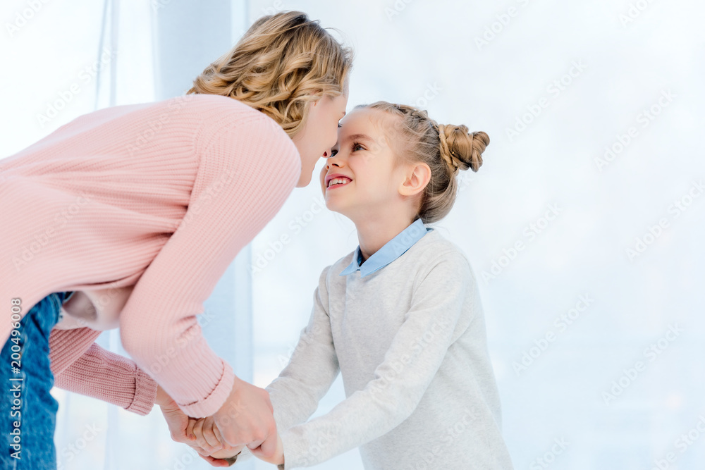 mother and daughter holding hands and touching with noses at home mother and daughter holding hands and touching with noses at home