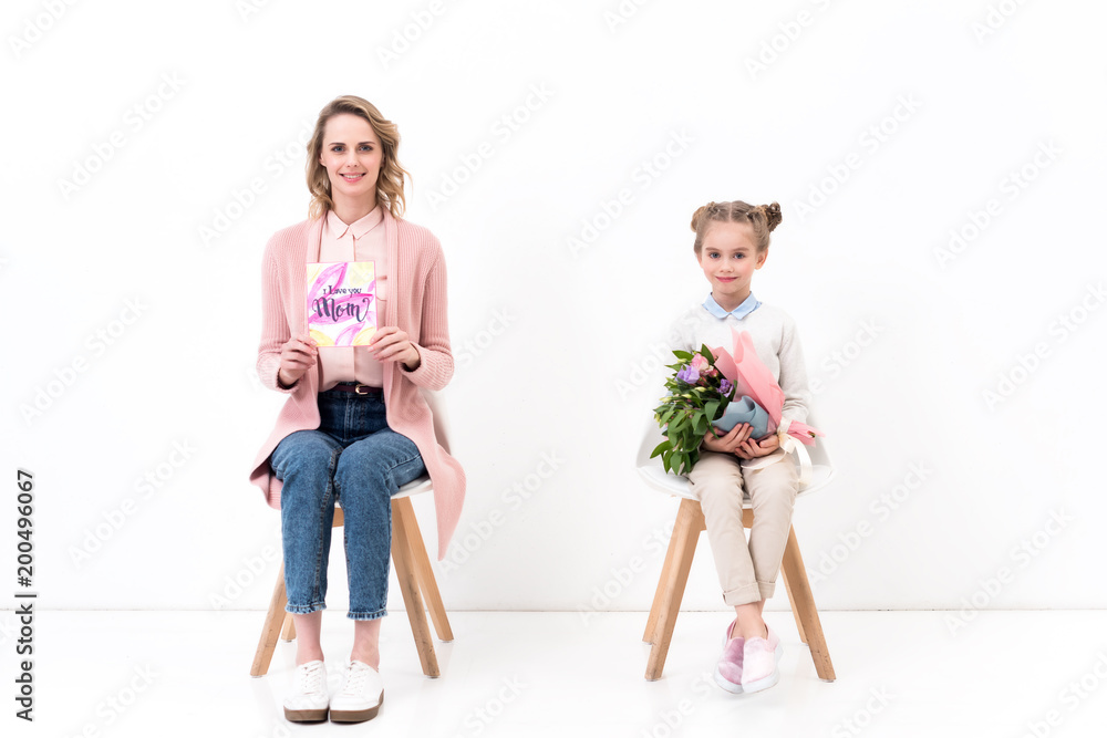 mother and daughter sitting on chairs and looking at camera on happy mothers day mother and daughter sitting on chairs and looking at camera on happy mothers day