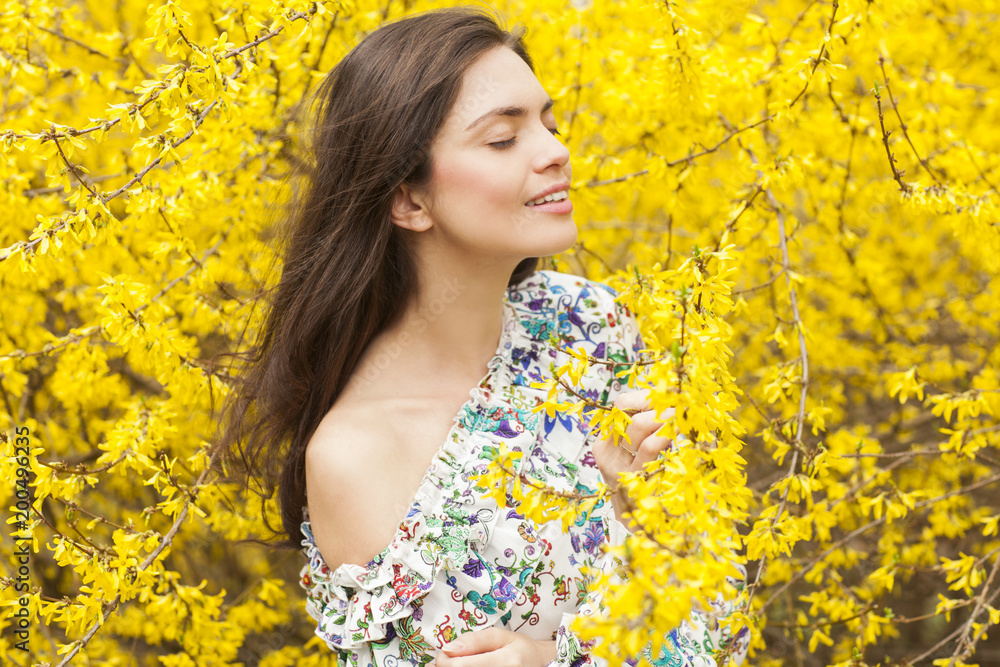 Young woman in the flowered, yellow garden in the spring time Young woman in the flowered, yellow garden in the spring time