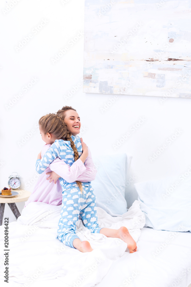 happy mother and daughter hugging in bedroom happy mother and daughter hugging in bedroom