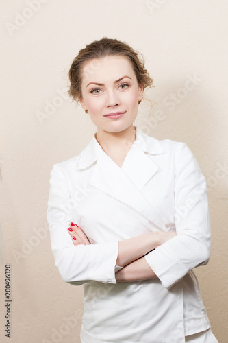 Girl cosmetician doctor in white lab coat against white wall.