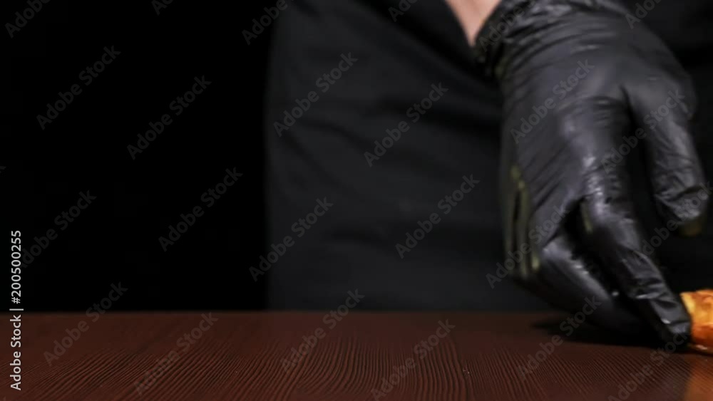 Burger is cooking on black background in black food gloves. Very luscious air bun and marbled beef. Restaurant where each burgers is cooked by hand. Salsa is put on roll. Not made ideal. Not conveyor Burger is cooking on black background in black food gloves. Very luscious air bun and marbled beef. Restaurant where each burgers is cooked by hand. Salsa is put on roll. Not made ideal. Not conveyor