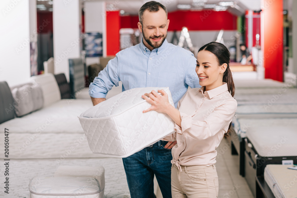 couple choosing folding mattress together in furniture store with arranged mattresses couple choosing folding mattress together in furniture store with arranged mattresses