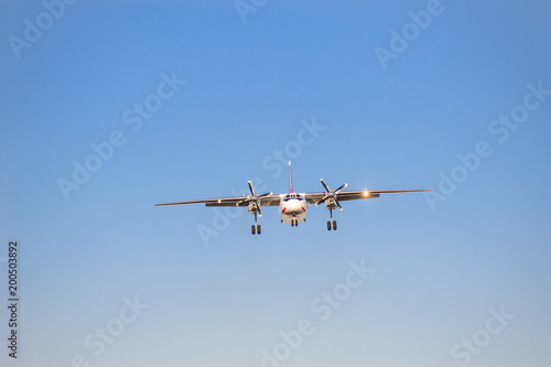 white airplane with screw engines with chassis released in the blue sky, front view