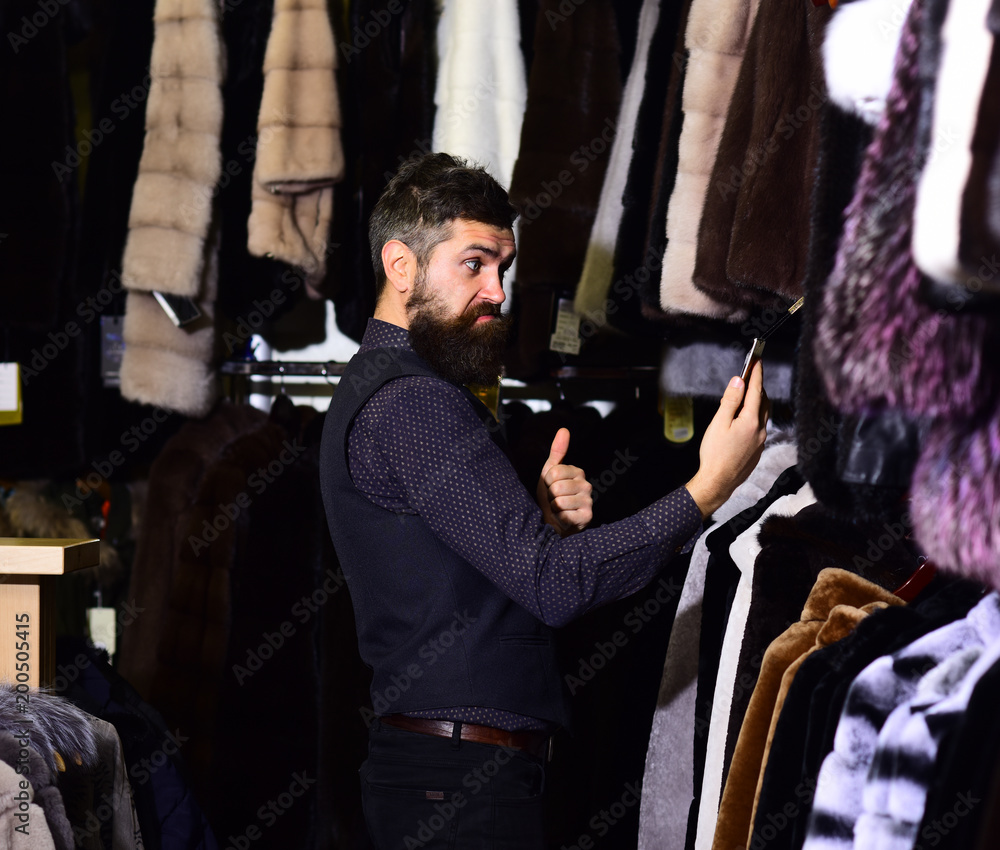Shopping consultant concept. Guy with surprised face looks at coat. Shopping consultant concept. Guy with surprised face looks at coat.