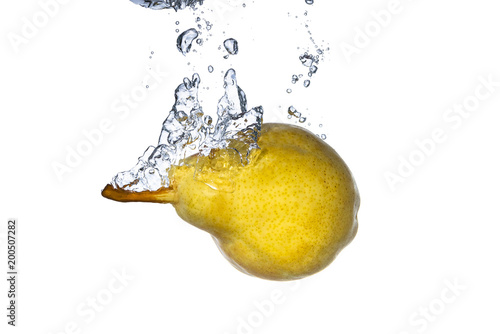 Ripe pear falling in water with splash and bubbles white isolated