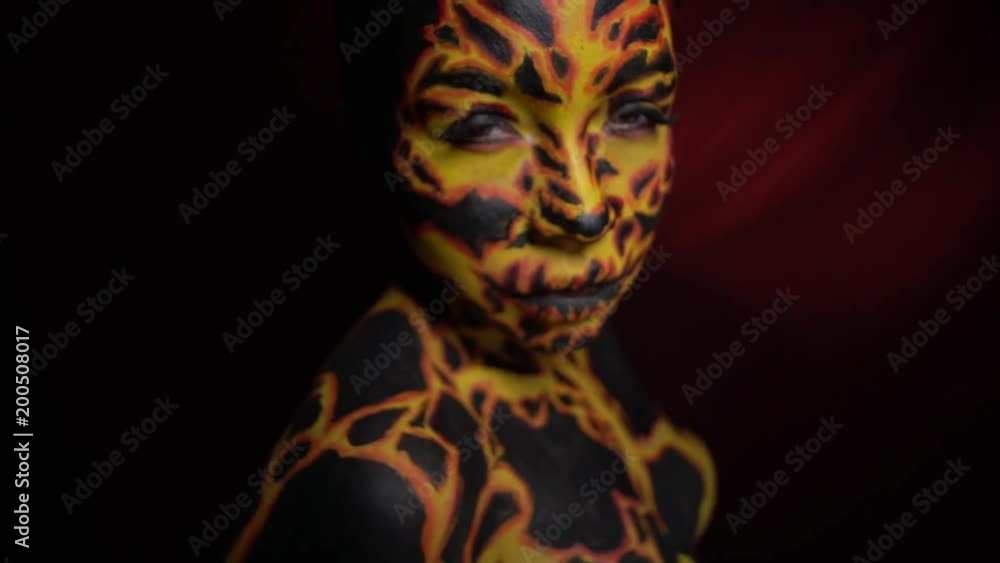 A girl with a bodypainting on her body in the image of a volcanic lava looks at her friend with displeasure A girl with a bodypainting on her body in the image of a volcanic lava looks at her friend with displeasure