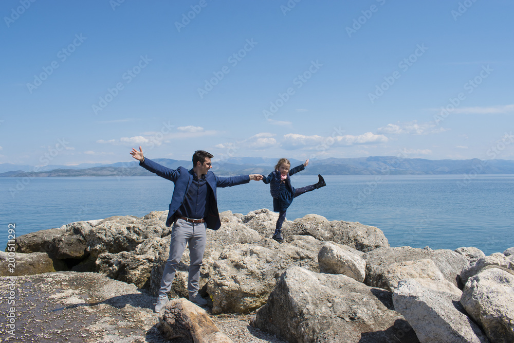 Father and daughter outdoors having fun, walking by the sea in a spring day. Corfu island, Greece. Father and daughter outdoors having fun, walking by the sea in a spring day. Corfu island, Greece.