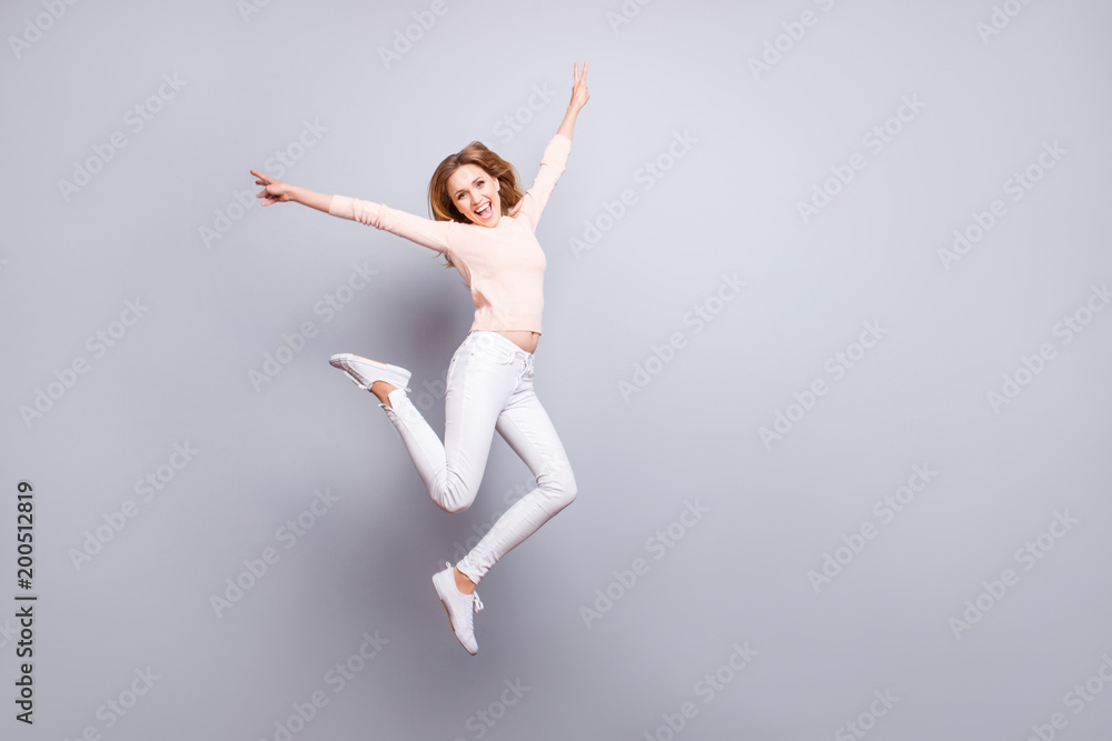 People emotion expressing feeling good mood person concept. Full-size portrait of excited cheerful joyful rejoicing delightful pretty woman jumping up showing v-sign isolated on gray background People emotion expressing feeling good mood person concept. Full-size portrait of excited cheerful joyful rejoicing delightful pretty woman jumping up showing v-sign isolated on gray background