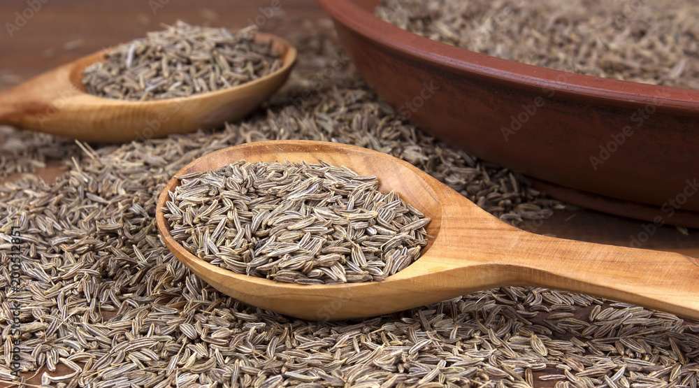 Cumin. Caraway seeds on wooden table. Cumin seeds in wooden spoon Cumin. Caraway seeds on wooden table. Cumin seeds in wooden spoon