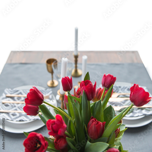 selective focus of bouquet of red tulips and rustic table setting behind photo