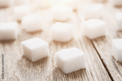 Cubes of white sugar on the wooden surface. Closeup, selective focus, toned