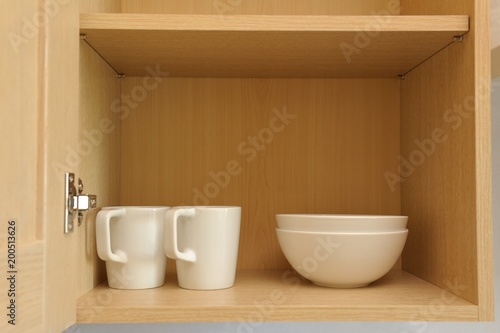 Different white dishes in cupboard in the kitchen. Scandinavian style.