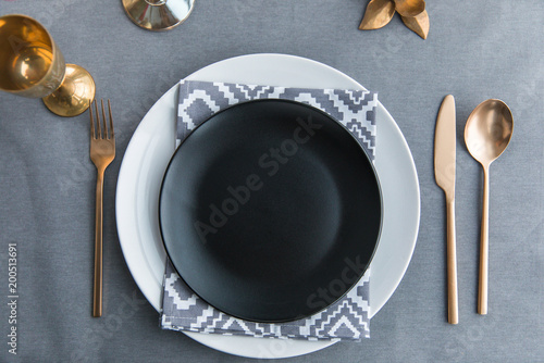 top view of black empty plate, napkin and old fashioned tarnished cutlery on tabletop