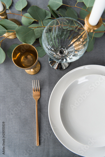 top view of rustic table setting with eucalyptus, old fashioned cutlery, candles in candle holder and empty plates photo