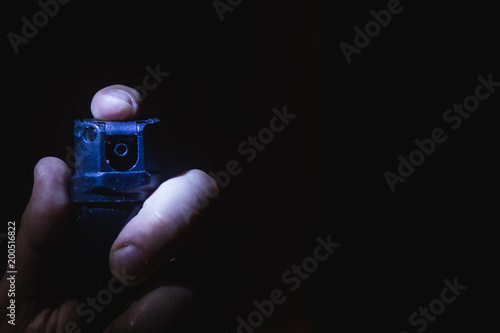 a man's hand holds a gas pepper spray in the dark, a black background. concept of safety and self-defense