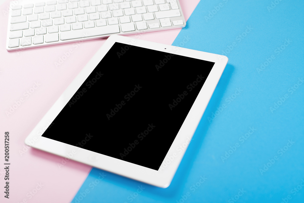 Computer keyboard next to tablet on pink and blue background. Technology. Computer keyboard next to tablet on pink and blue background. Technology.
