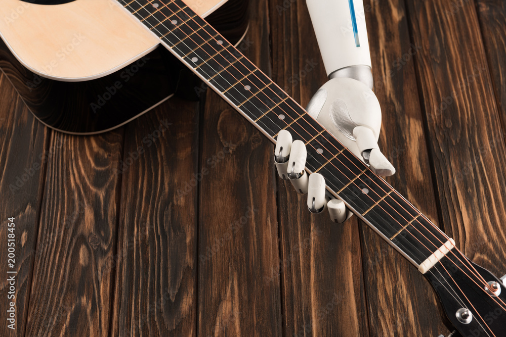 Fototapeta premium cropped shot of robot playing acoustic guitar over wooden surface