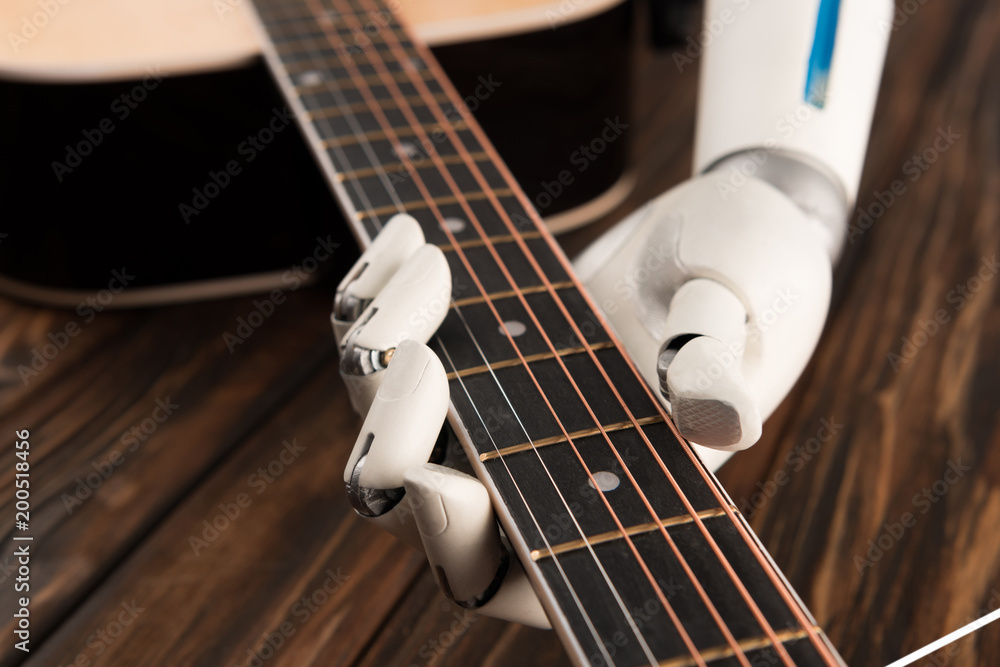cropped shot of robot playing guitar over wooden surface - obrazy, fototapety, plakaty 