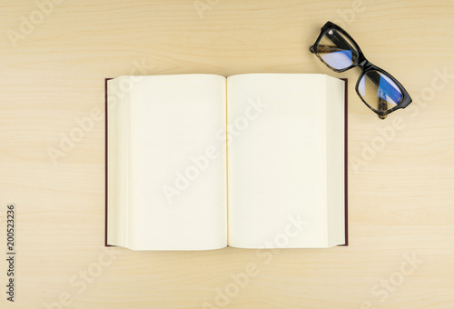 top view of the opened blank book with an eyeglasses on the wooden table