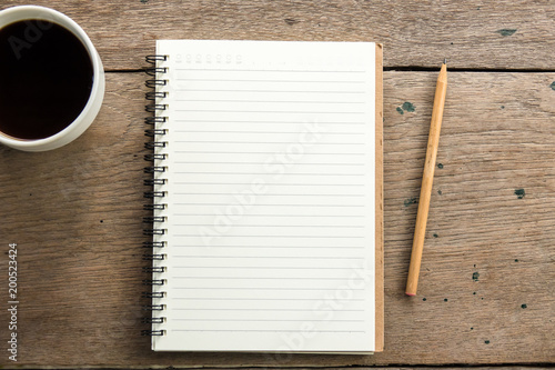 Top view of blank notebook with white coffee and natural light on wooden table. photo