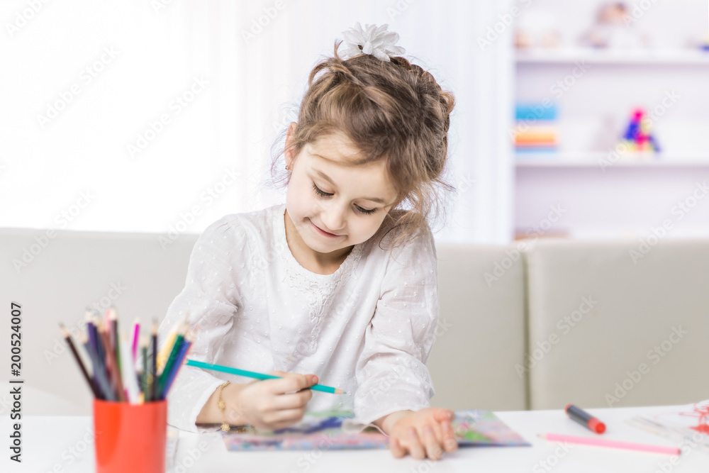 five year old girl draws with crayons sitting at table in the nursery five year old girl draws with crayons sitting at table in the nursery