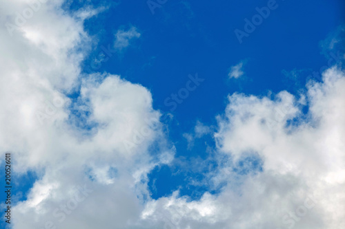 Background of transparent white clouds in a light blue sky illuminated by the sun.