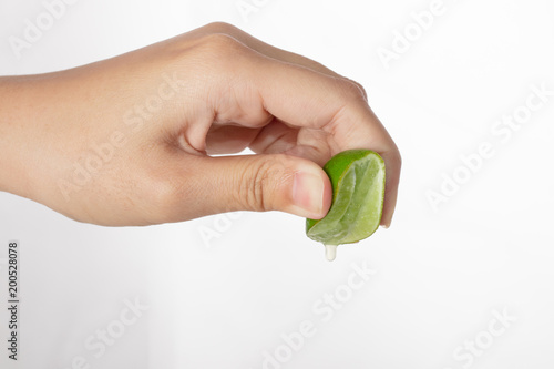Hand squeeze green lime with lime drop isolated on white background.