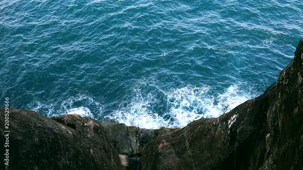 Waves on the Sea. Top view from the rocks of the Sea surface. Beautiful deep blue Ocean Water background. Black impregnable rocks Waves on the Sea. Top view from the rocks of the Sea surface. Beautiful deep blue Ocean Water background. Black impregnable rocks