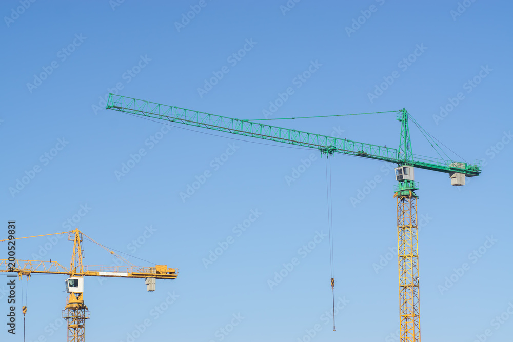 Construction cranes on the background of clear blue sky Construction cranes on the background of clear blue sky