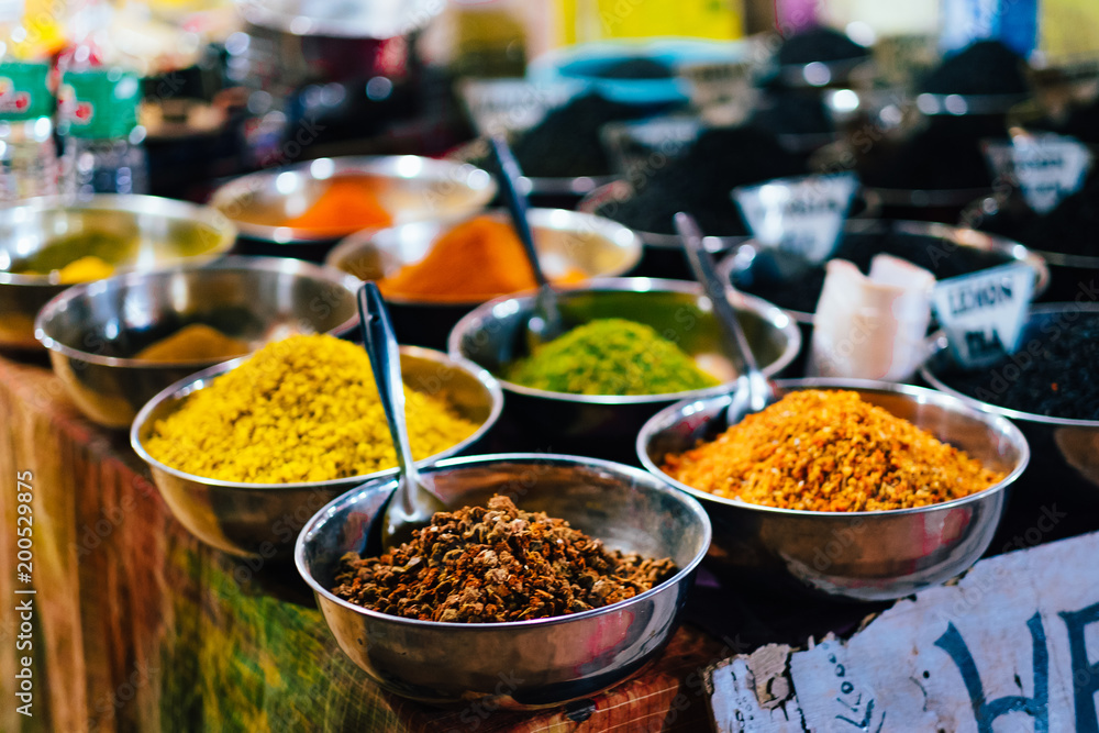 Indian spices in shiny metal bowls put for sale on a vendors table