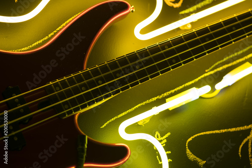 Bass guitar in yellow neon light, music bar sign, wallpaper