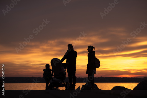 Father and mother with a baby in a stroller and children