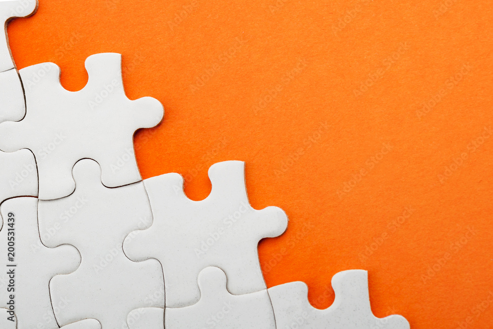 Obraz premium Jigsaw puzzle pieces and business concept with a border made of puzzle pieces on colorful bright orange background with copy space