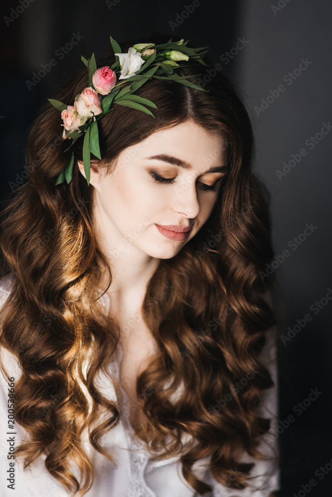 Morning of the bride. Beautiful portrait of a bride in a peignoir with hair curls and fresh flowers