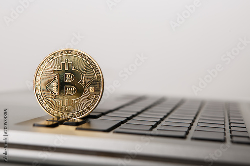 Golden Bitcoin - New virtual money on notebook. A visual representation of digital cryptocurrencies. Bitcoin are fully dematerialized and decentralized electronic currencies. Shallow depth of field. photo