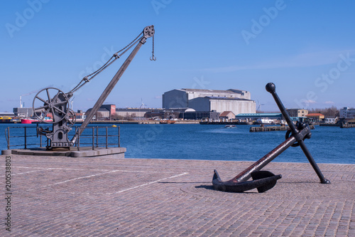 An anchor and a wharfside crane are now used as decoration along the waterfront in Copenhagen, Denmark photo