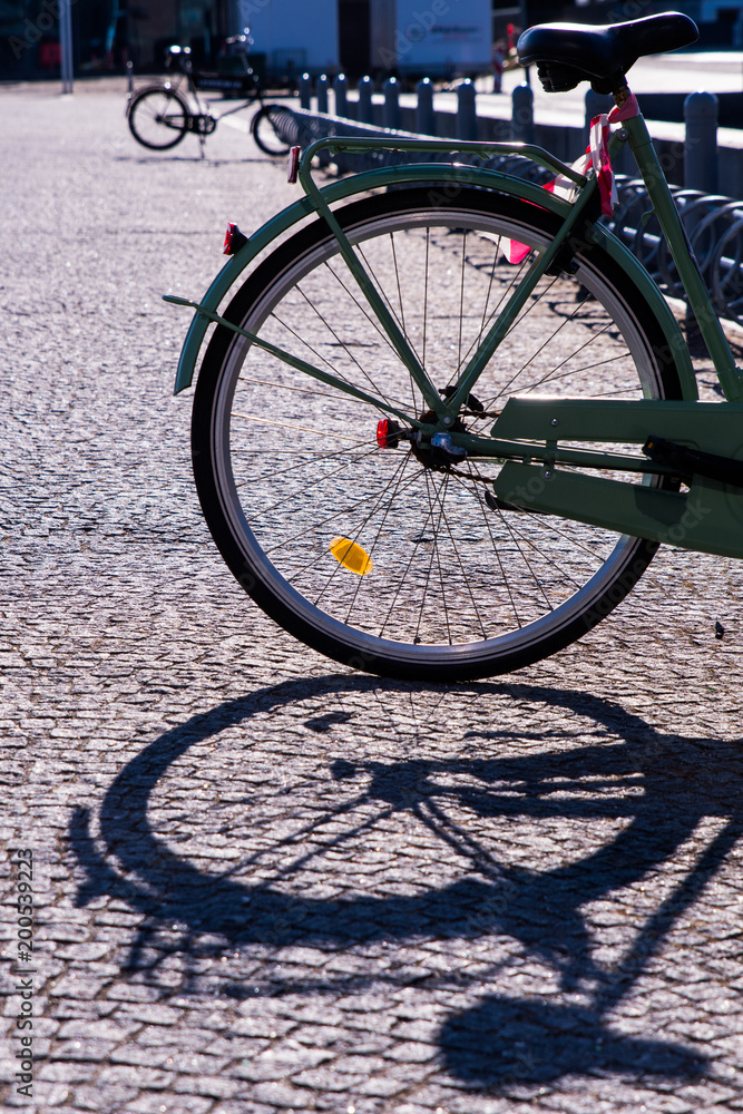 The rear wheel of a bicycle casts a shadow on the cobbled path The rear wheel of a bicycle casts a shadow on the cobbled path