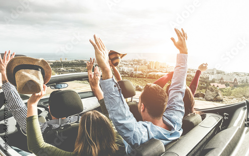 Happy friends with hands up having fun in convertible car on summer vacation 
