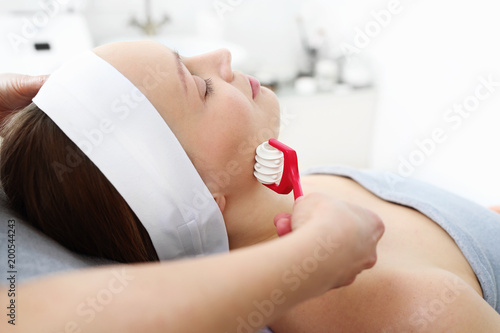 Relaksacyjny masaż twarzy. Kosmetyczka wykonuje masaż na twarzy kobiety. photo