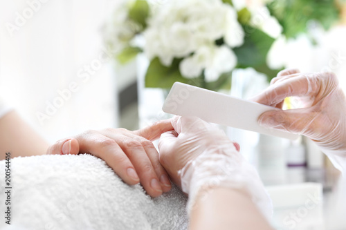 Pielęgnacja dłoni i paznokci. Kobieta na zabiegu manicure w salonie kosmetycznym photo