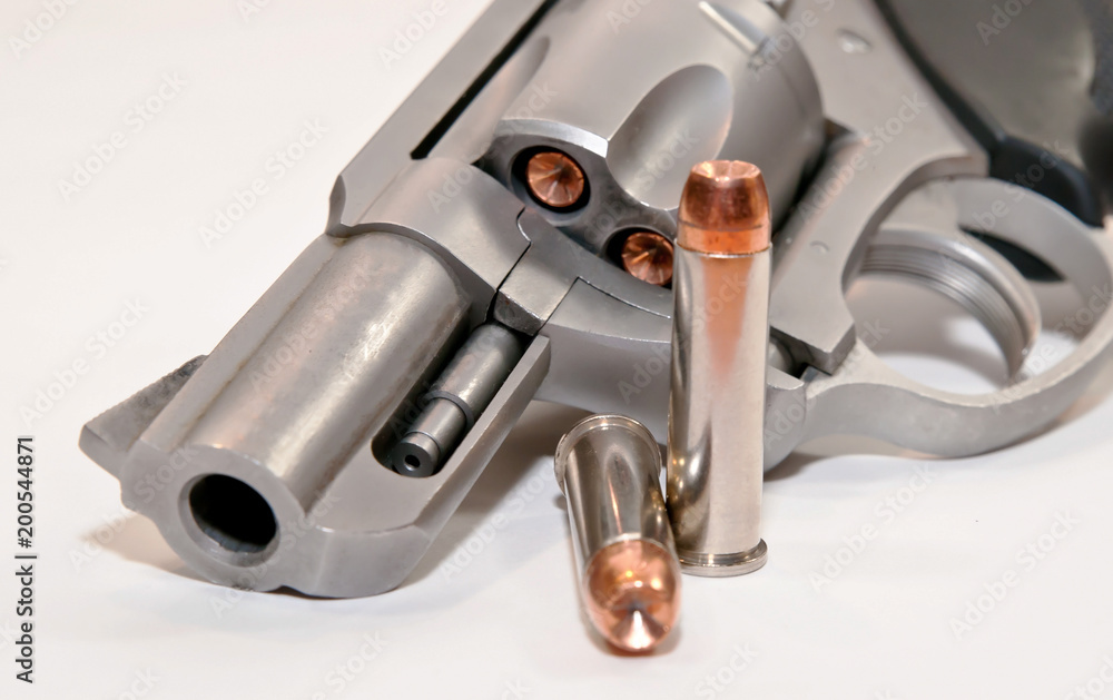 A .357 magnum revolver loaded with hollow point bullets with two shown next to the gun with a white background