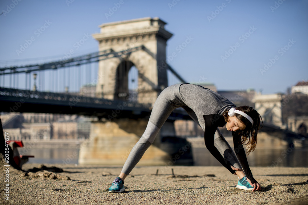 Woman in sportswear stretching on Danube river promenade in Budapest