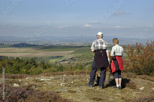 Ein aelteres Paar steht auf dem Huegel der Heidelandschaft im Naturschutzgebiet "am Horn" bei Siefersheim in Rheinhessen und schaut ueber die Landschaft.